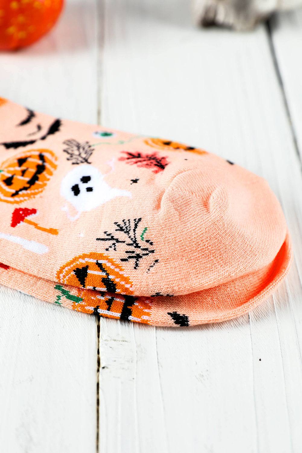 Stack of Halloween-themed socks on a white wooden surface