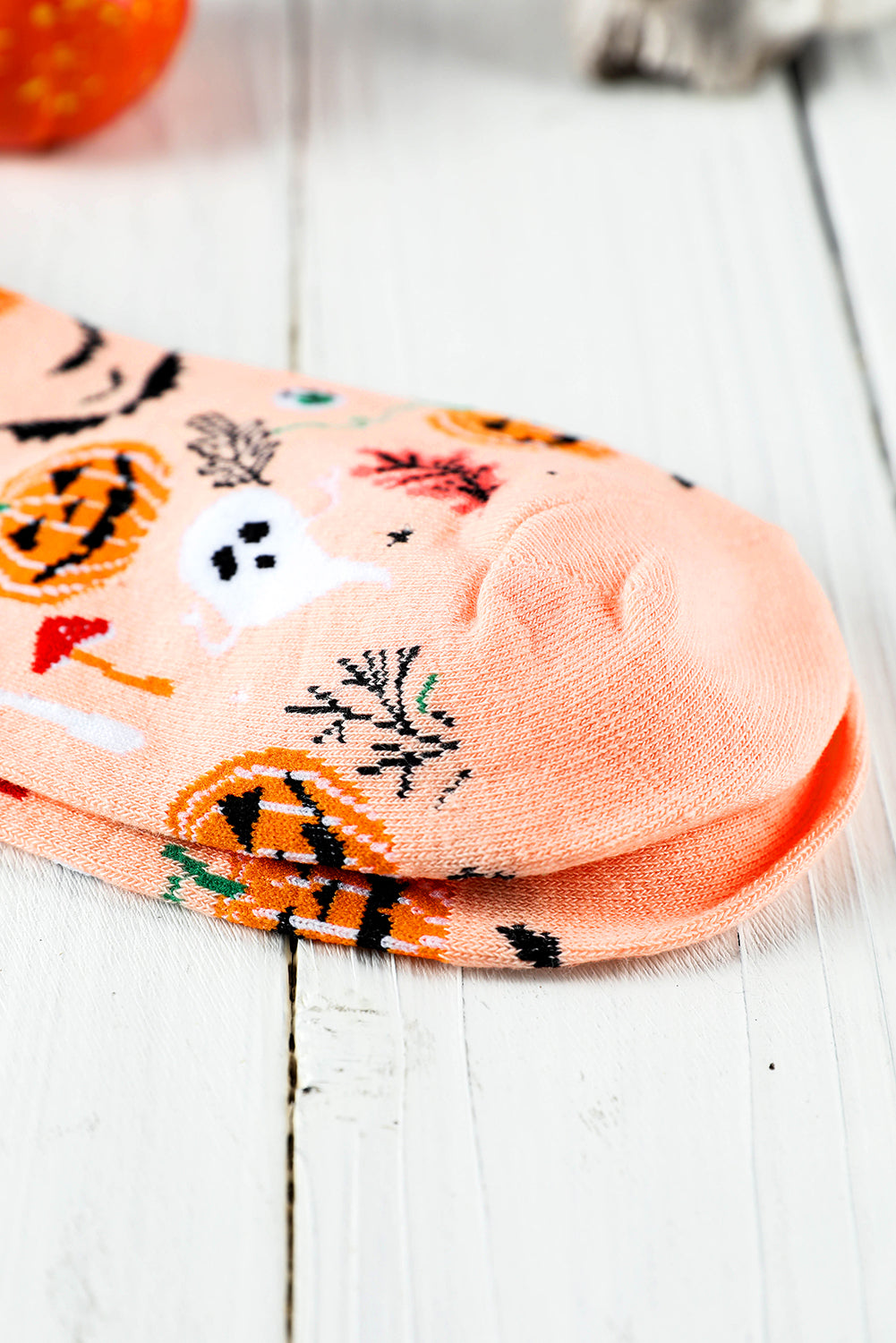 Stack of Halloween-themed socks on a white wooden surface