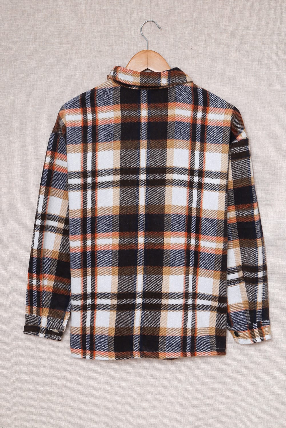 Plaid shirt on a hanger against a plain background